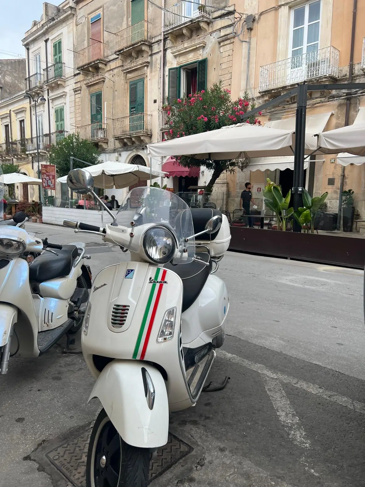 White Vespa scooter parked in Catania with historic buildings
